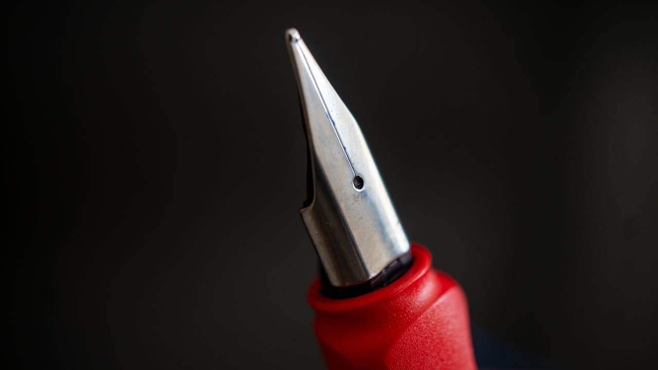 Detailed shot of a fountain pen nib against a black background, highlighting its metallic features.