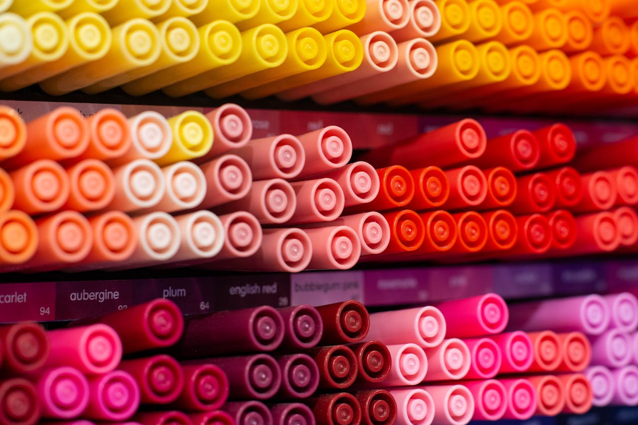 Close-up of a collection of vibrant colored art pens arranged neatly, showcasing a gradient of red, orange, and yellow hues.