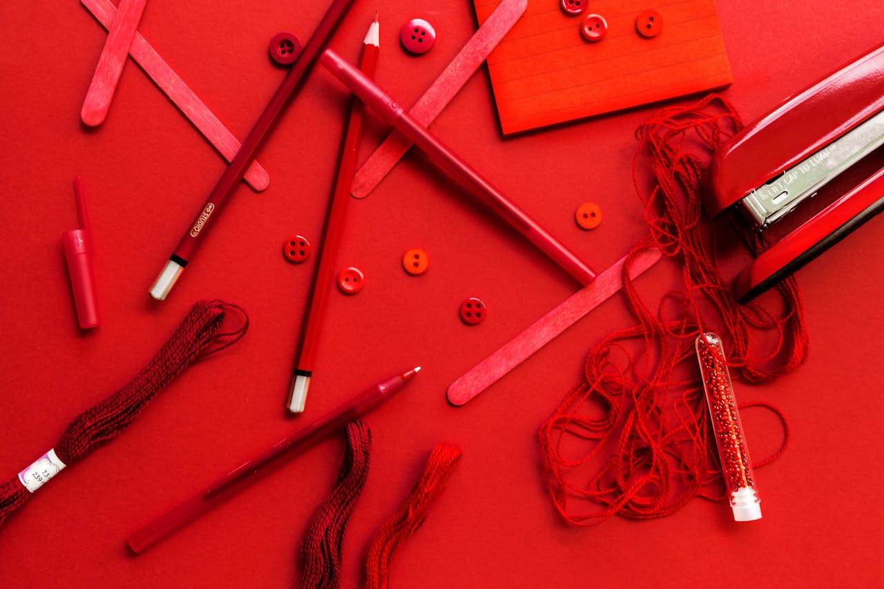 A vivid collection of red stationery and tools on a seamless red backdrop.